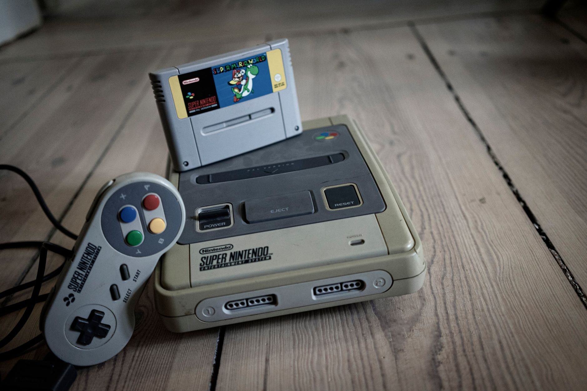 Retro video game console with controller on wooden surface — the spirit of the games that inspired Champignon Studios