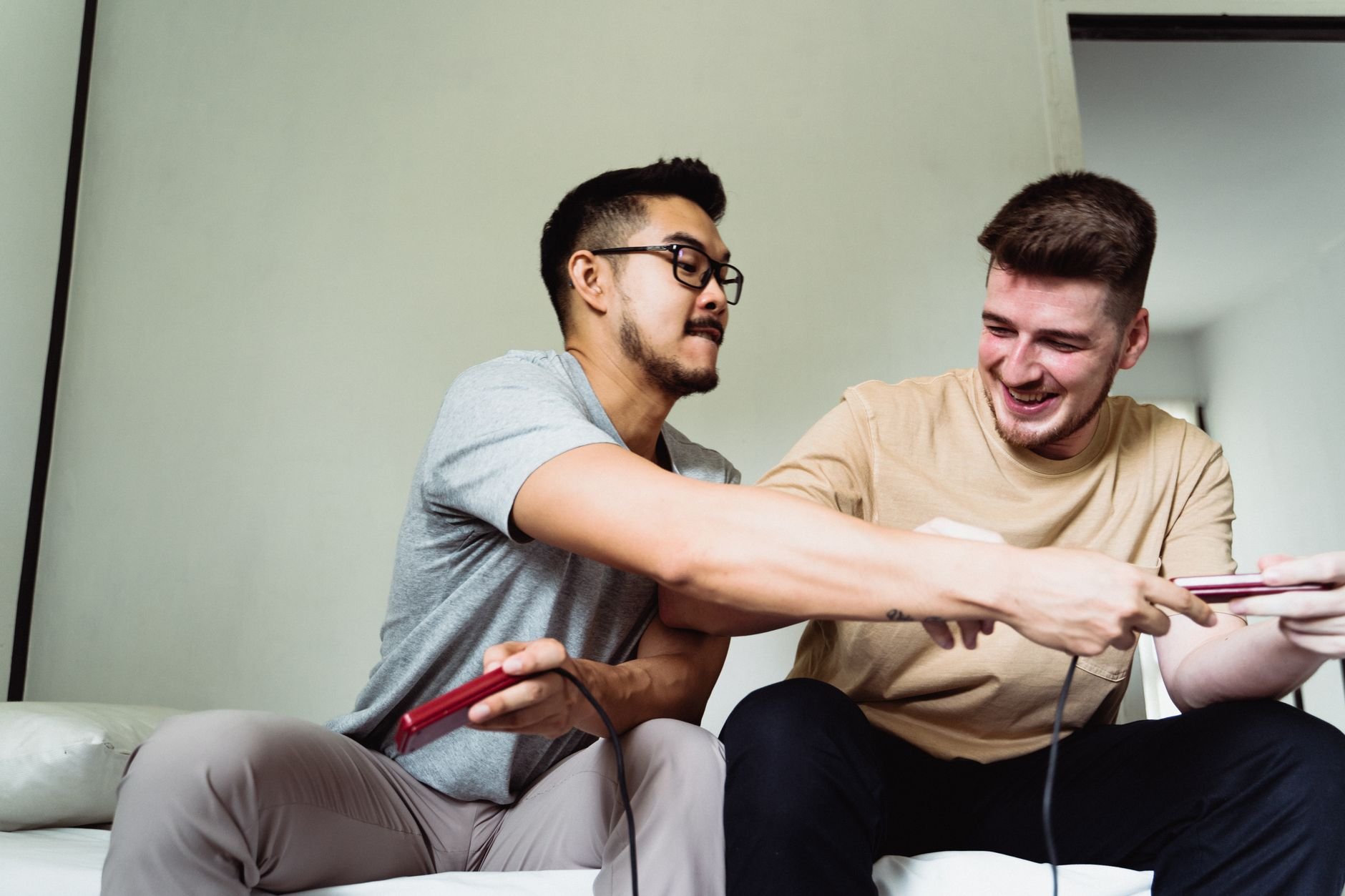 Two friends laughing and playing video games on a couch — the community around Champignon Studios